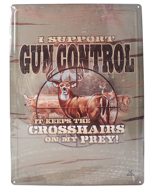 Metal sign with a deer and text about gun control on a wooden background