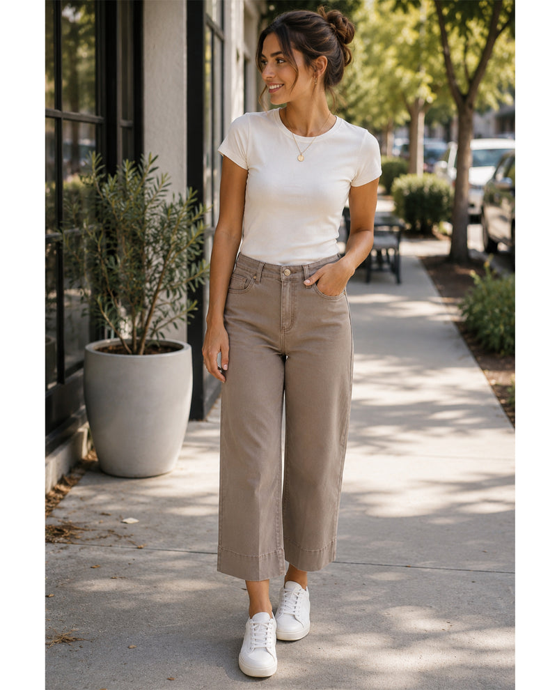 Woman wearing a white t-shirt and beige pants walking on a sidewalk.