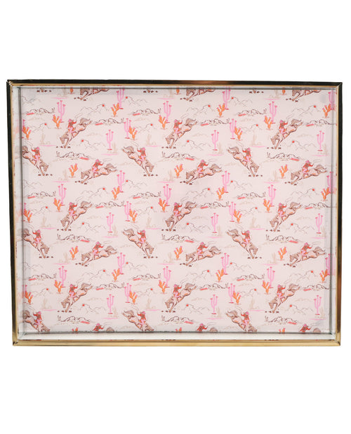 A square framed print featuring a repeating desert pattern with pink cacti, brown and gray mountains, and a light pink background, bordered by a thin metallic frame.