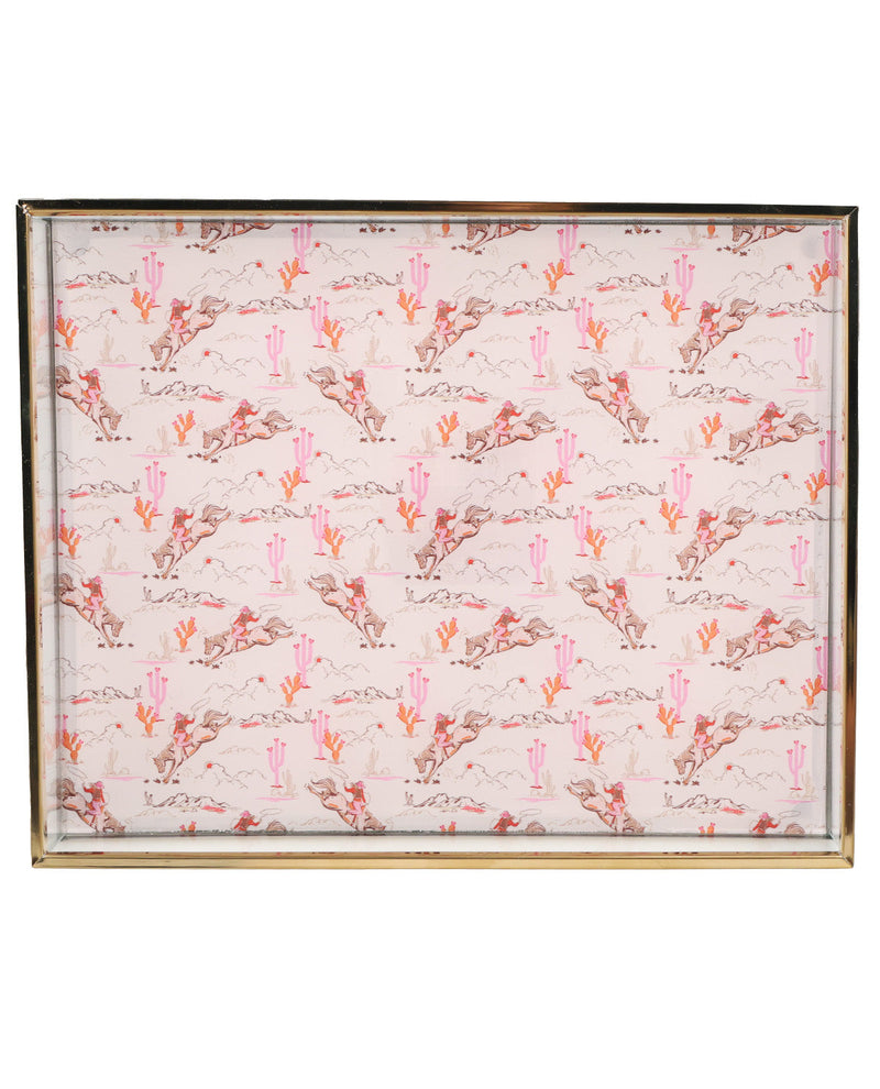 A square framed print featuring a repeating desert pattern with pink cacti, brown and gray mountains, and a light pink background, bordered by a thin metallic frame.