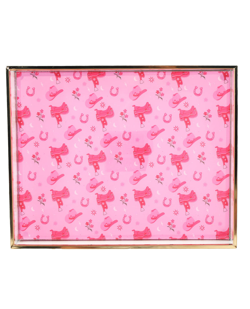 A rectangular picture frame with a gold-toned metal border, filled with a pink western-themed pattern featuring cowboy boots, horseshoes, and small flowers.