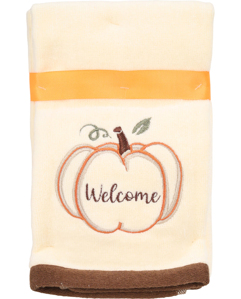 Folded towel with pumpkin design and 'Welcome' text on a white background