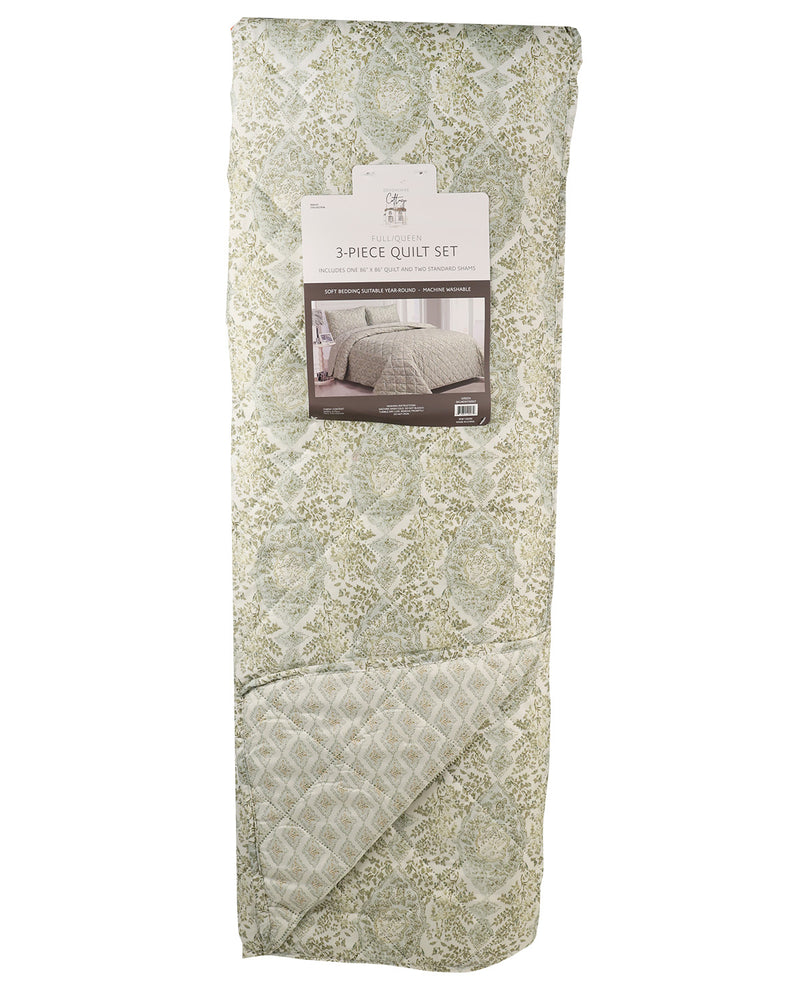 A folded 3-piece quilt set by Bella+Canvas, featuring a light sage green and beige floral damask pattern with a diamond-quilted texture, shown with its retail paper label on a white background.