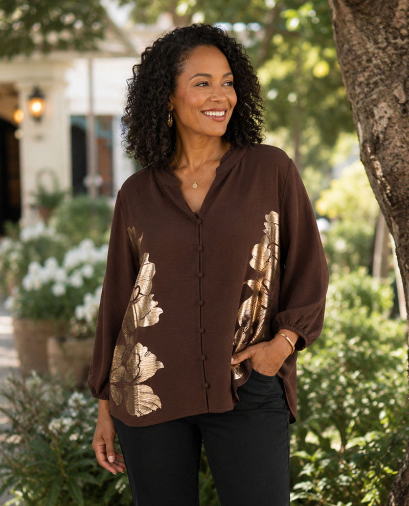 Woman wearing a brown blouse with floral patterns outdoors