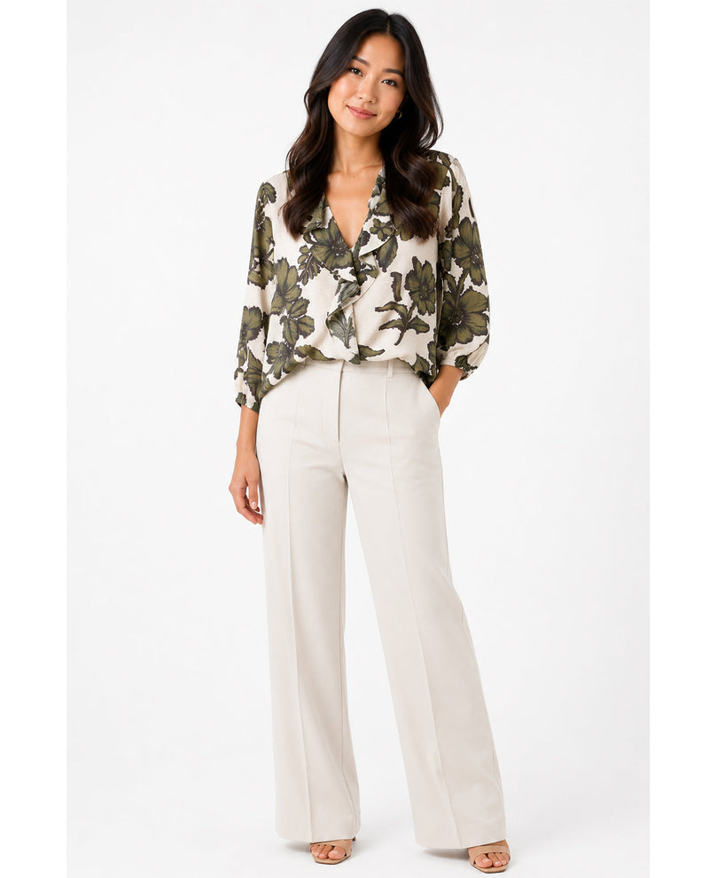 Woman wearing a floral blouse and white pants on a white background