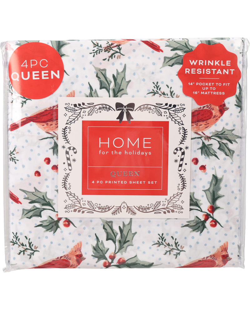 A packaged bedding set labeled 'HOME for the holidays' with a white background and holiday print featuring red birds, holly leaves, pinecones, and small red berries. Red circular callouts read '4PC QUEEN' and 'WRINKLE RESISTANT'.