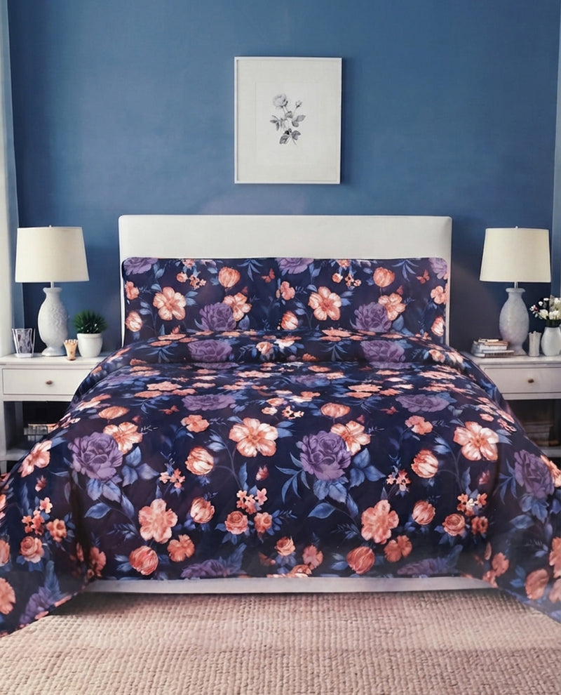 A floral comforter set with matching pillowcases in a bedroom setting. The comforter and pillows feature a dark navy blue background with large pink, purple, and orange flowers.