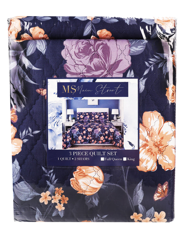 A packaged quilt set from Main Street MSA, featuring a navy blue background with a floral pattern in lavender, peach, and gray. The packaging has a clear window showing the quilt and shams inside.