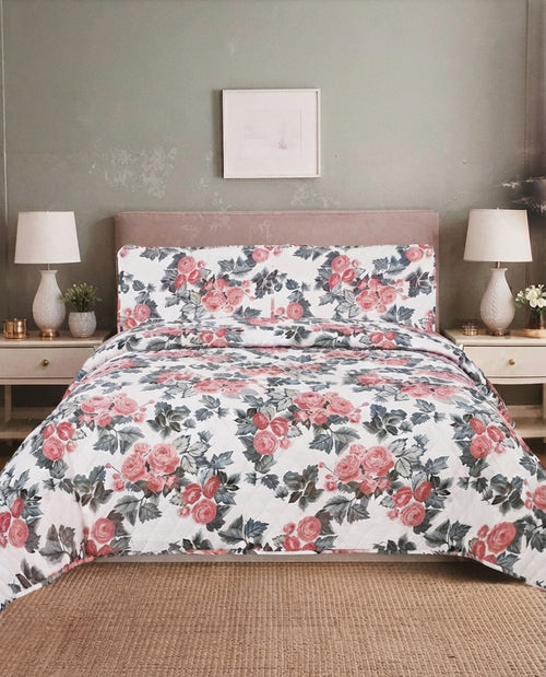 A floral bedding set featuring a duvet cover and two matching pillowcases with a pink rose and green leaf pattern on a white background, styled on a bed in a bedroom setting.