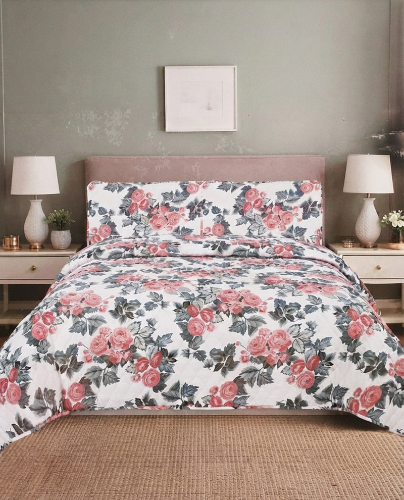 A floral bedding set featuring a duvet cover and two matching pillowcases with a pink rose and green leaf pattern on a white background, styled on a bed in a bedroom setting.