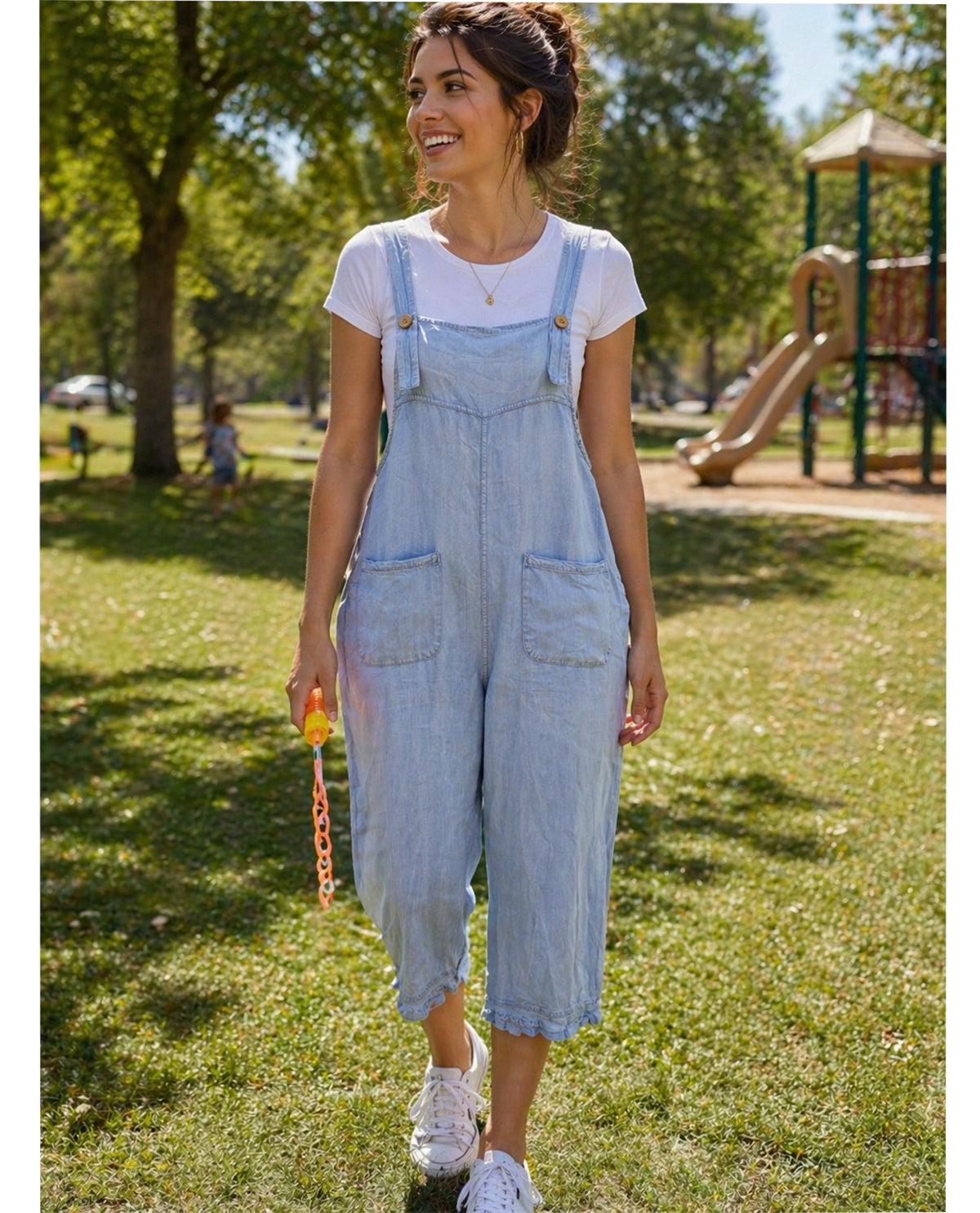 Woman wearing light blue denim overalls in a park