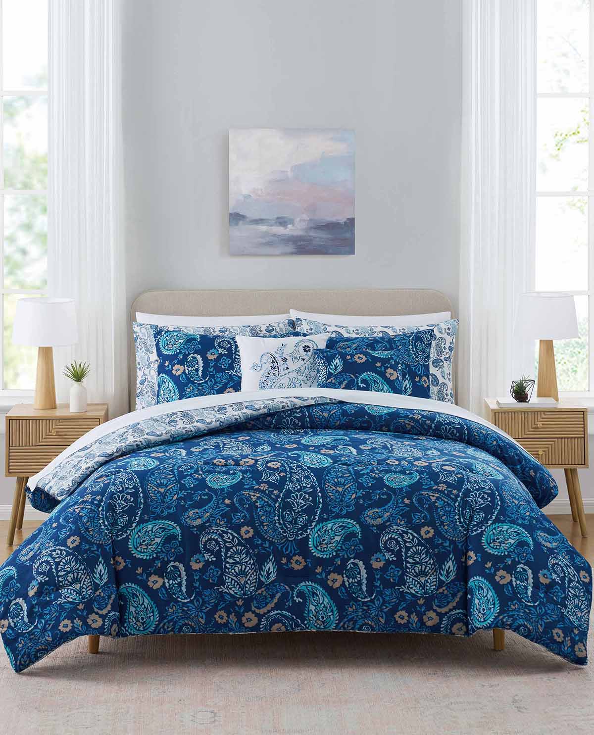 Blue paisley comforter set on a bed in a bright bedroom with white walls and natural light.