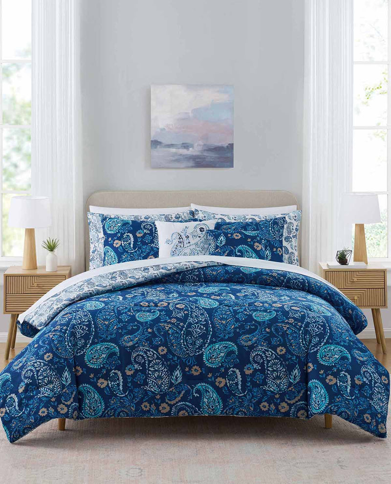 Blue paisley comforter set on a bed in a bright bedroom with white walls and natural light.