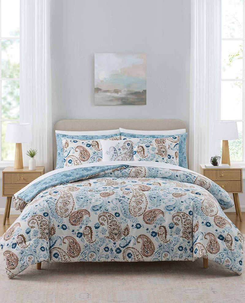Floral patterned comforter set on a bed in a bright bedroom with light gray walls.
