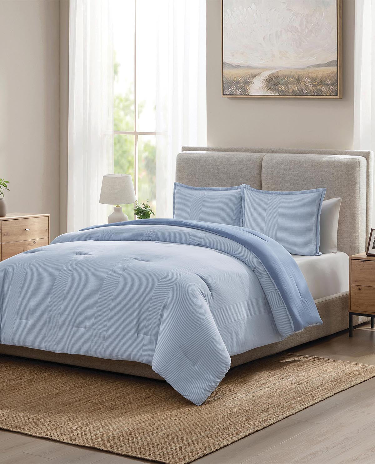 Light blue comforter set on a bed in a bedroom with a neutral color scheme.