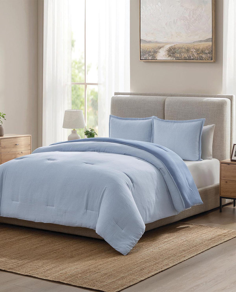 Light blue comforter set on a bed in a bedroom with a neutral color scheme.