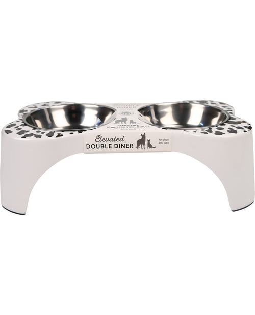 A white elevated double pet feeder and waterer with stainless steel bowls, featuring a black and white leopard print pattern on the sides and a central label that reads 'Elevated DOUBLE DINER'.