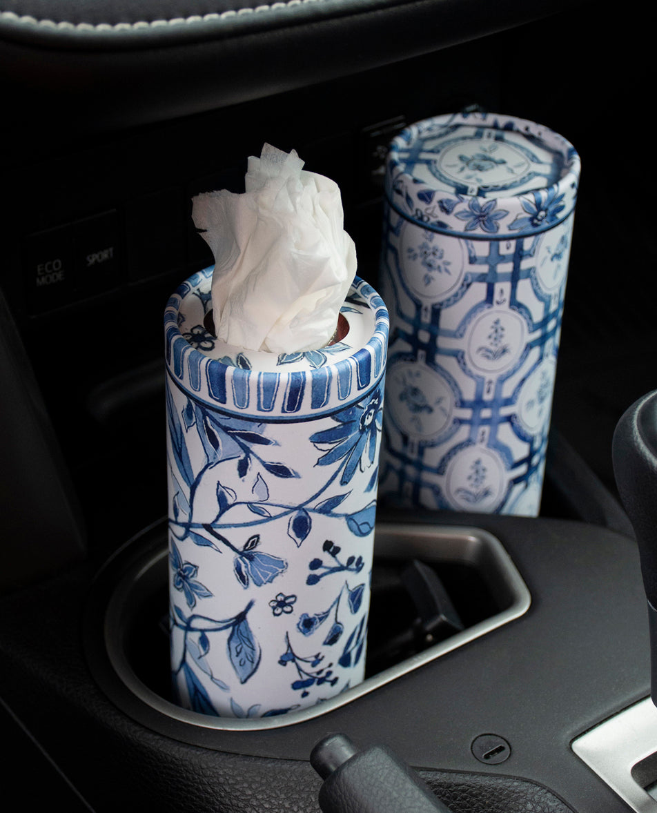 Blue and white patterned tissue holder with tissues in a car's cup holder.