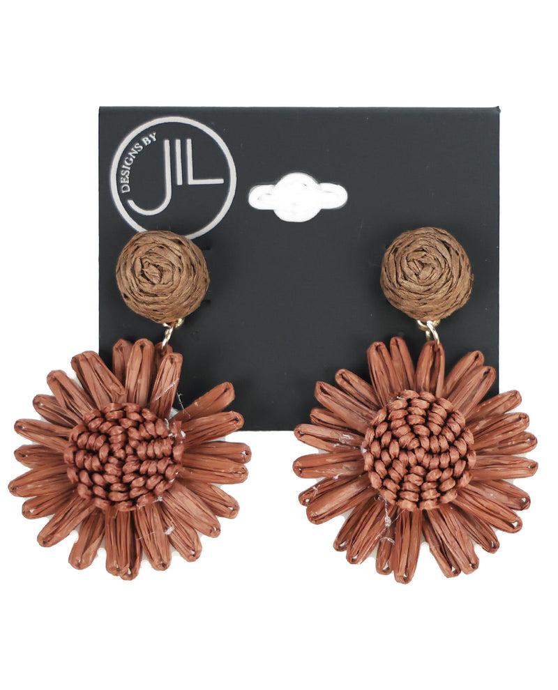 A pair of Discovery by JIL woven straw dangle earrings shaped like sunflowers, displayed on a black brand card against a white background.