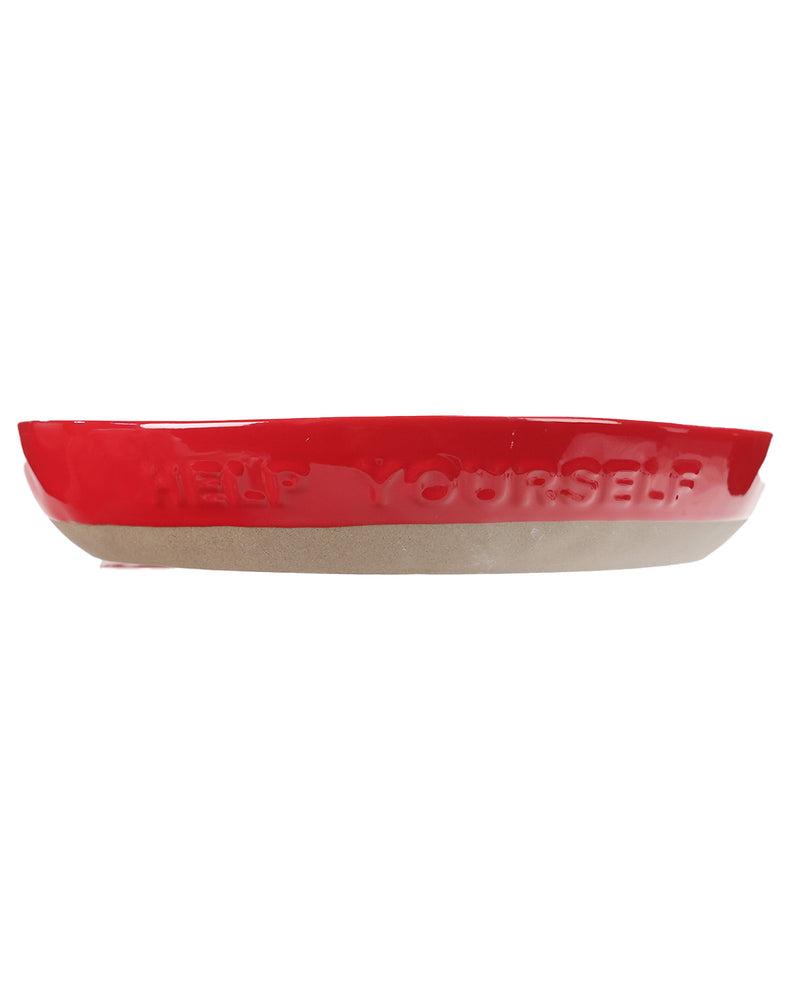 A glossy red ceramic dish with 'HELP YOURSELF' embossed on the rim, set against a plain white background.