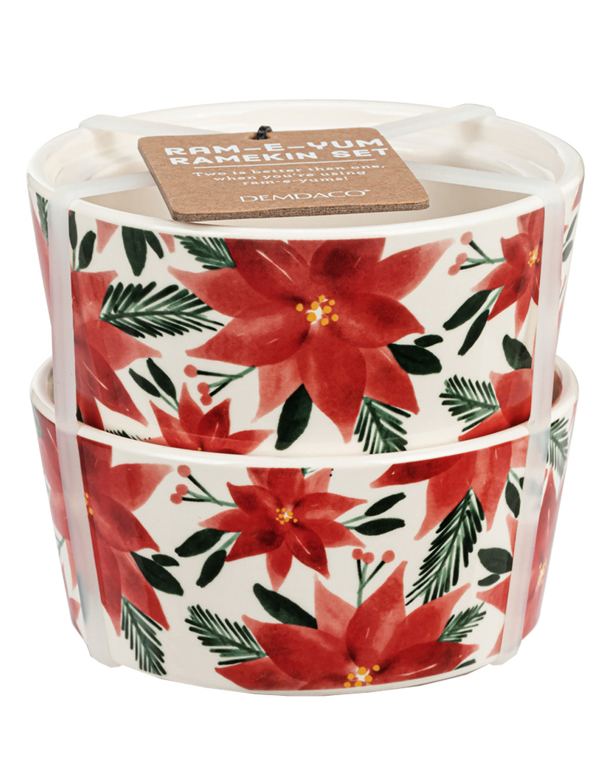A set of two stacked ramekins with a white base decorated with a red poinsettia and green pine branch pattern. A brown paper tag is attached to the top candle lid.