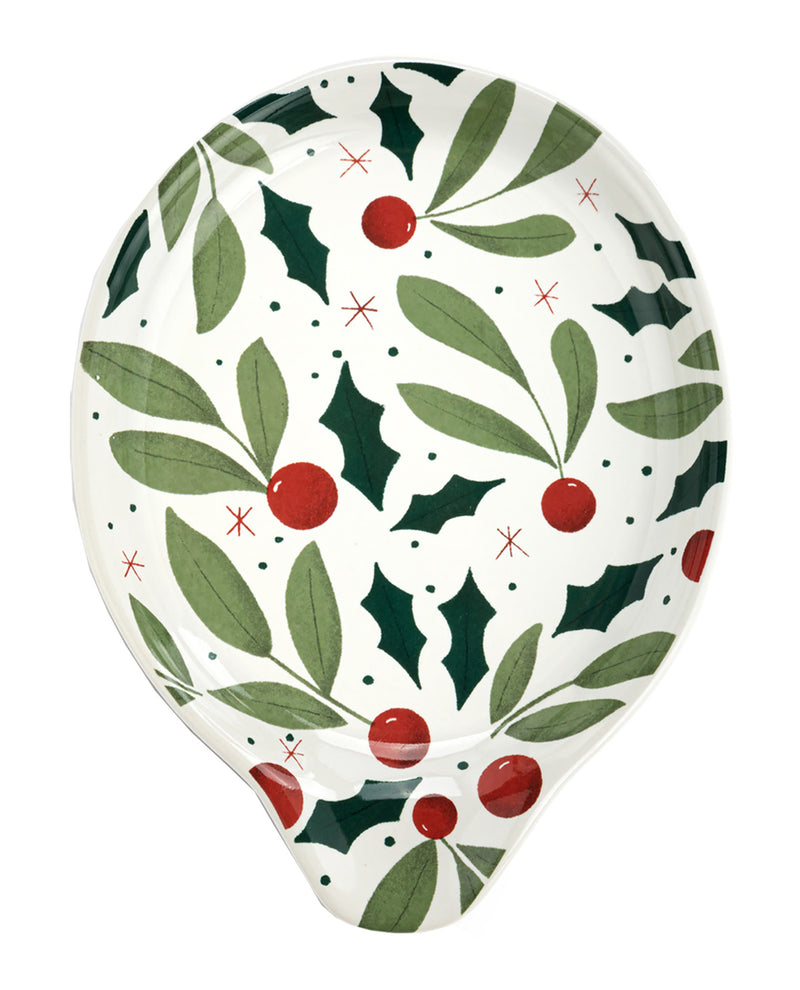 A holiday-themed teardrop-shaped dish or spoon rest featuring a festive pattern of green holly leaves, red berries, and small red stars on a white background.