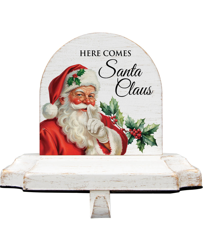 Decorative sign with Santa Claus and 'Here Comes Santa Claus' text on a white background
