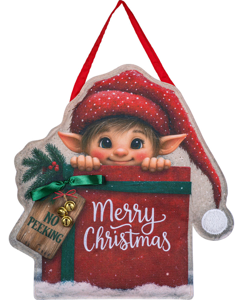 A Christmas hanging ornament shaped like a gift box with a peeking elf face, red Santa hat, green ribbon, snow-dusted edges, and a wooden tag that reads 'NO PEEKING Merry Christmas' on a white background.