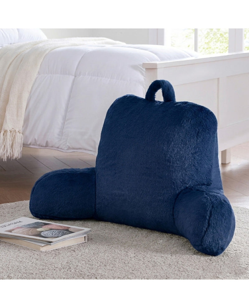 Navy blue backrest pillow on a bed with a book next to it