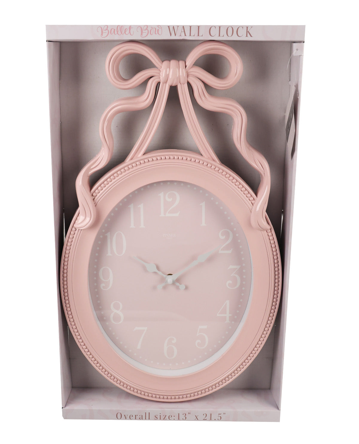 A pastel pink wall clock with a decorative bow-shaped top and a round face, shown inside its retail packaging box against a white background.