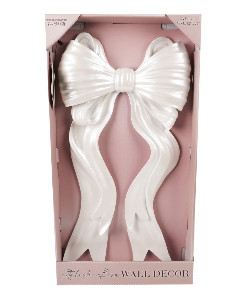 A large white faux-hair bow wall decor piece displayed inside a pink retail box. The product has long, wavy strands gathered into a oversized bow, and the packaging shows the brand name 'Stylish Fen' and the text 'WALL DECOR'.