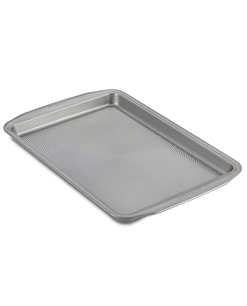 A rectangular metal baking pan with raised rim and a textured, ribbed interior surface, shown at an angle on a plain white background.
