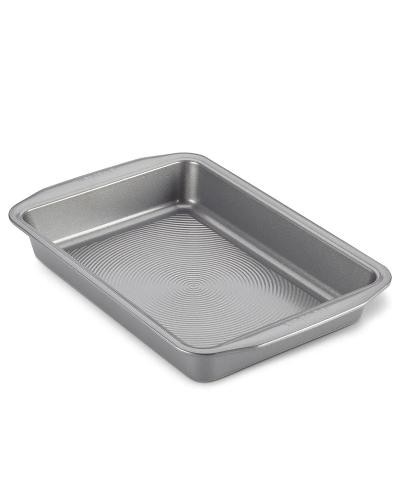 A rectangular metal baking pan with a textured, ribbed interior and raised rim, shown at an angle on a white background.
