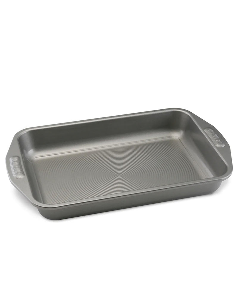 A rectangular gray non-stick baking pan with rounded corners and side handles, featuring a textured circular pattern on the bottom, shown on a plain white background.