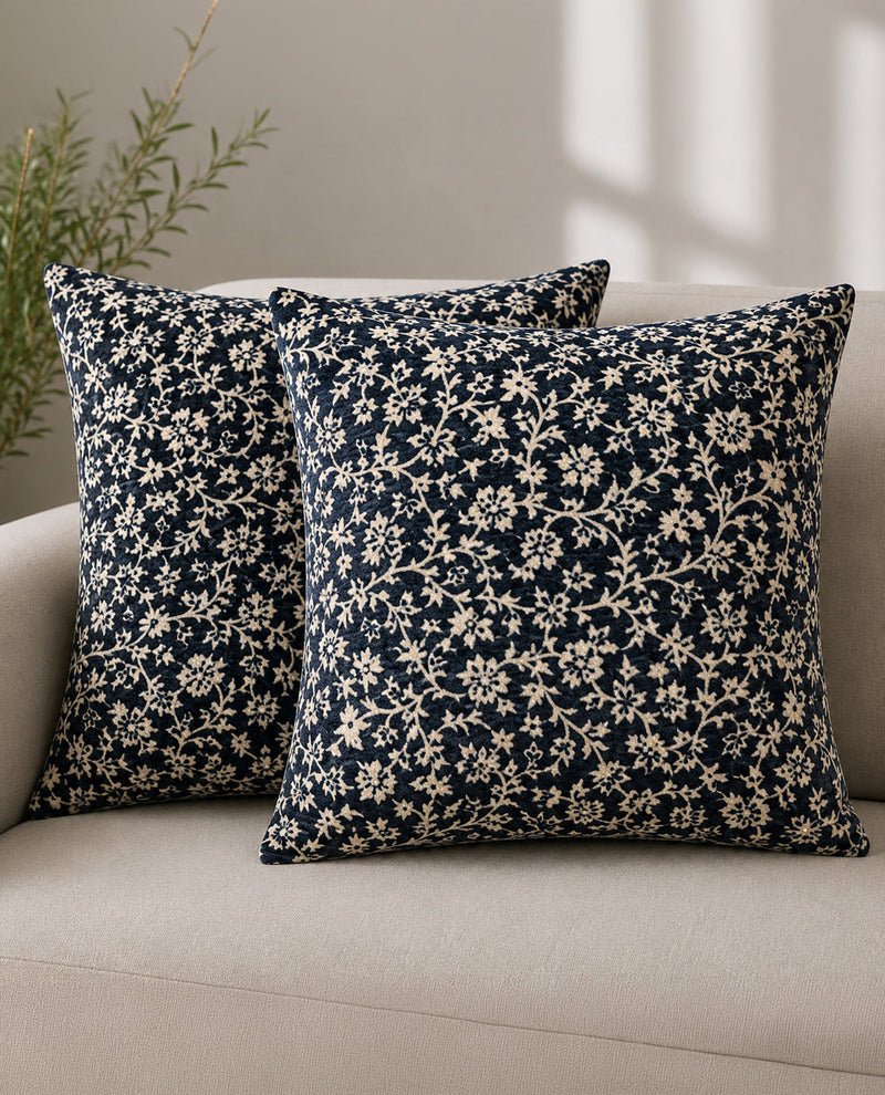 Two navy blue floral patterned pillows on a beige sofa.