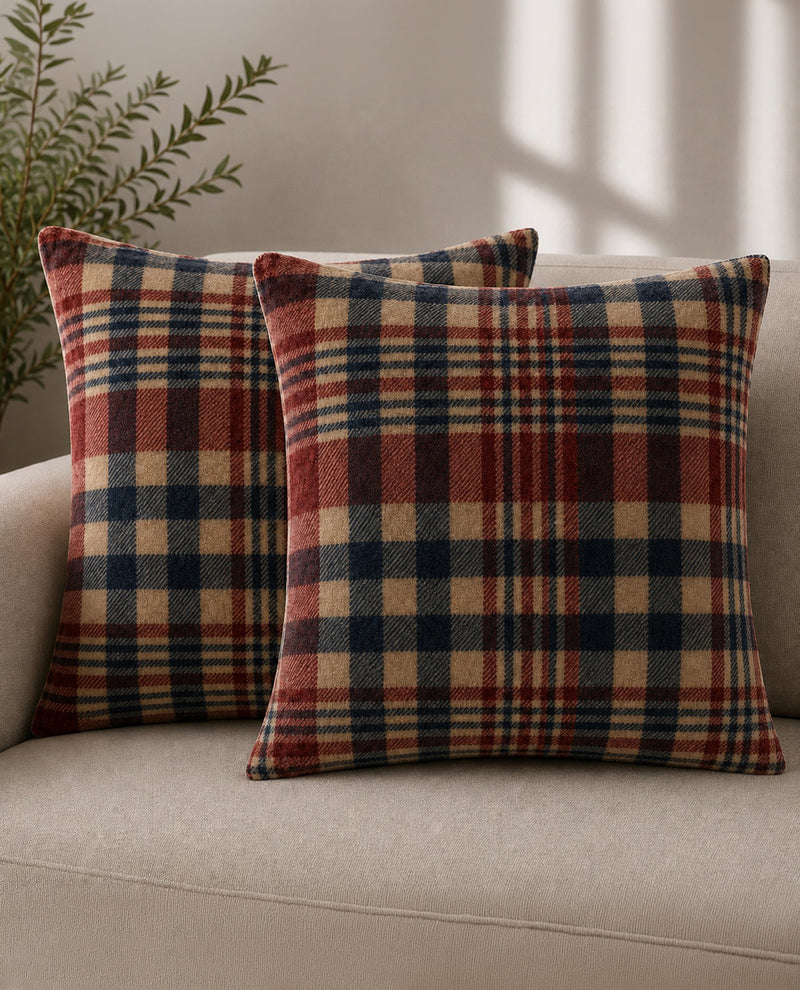 Plaid patterned pillows on a beige sofa with a plant in the background