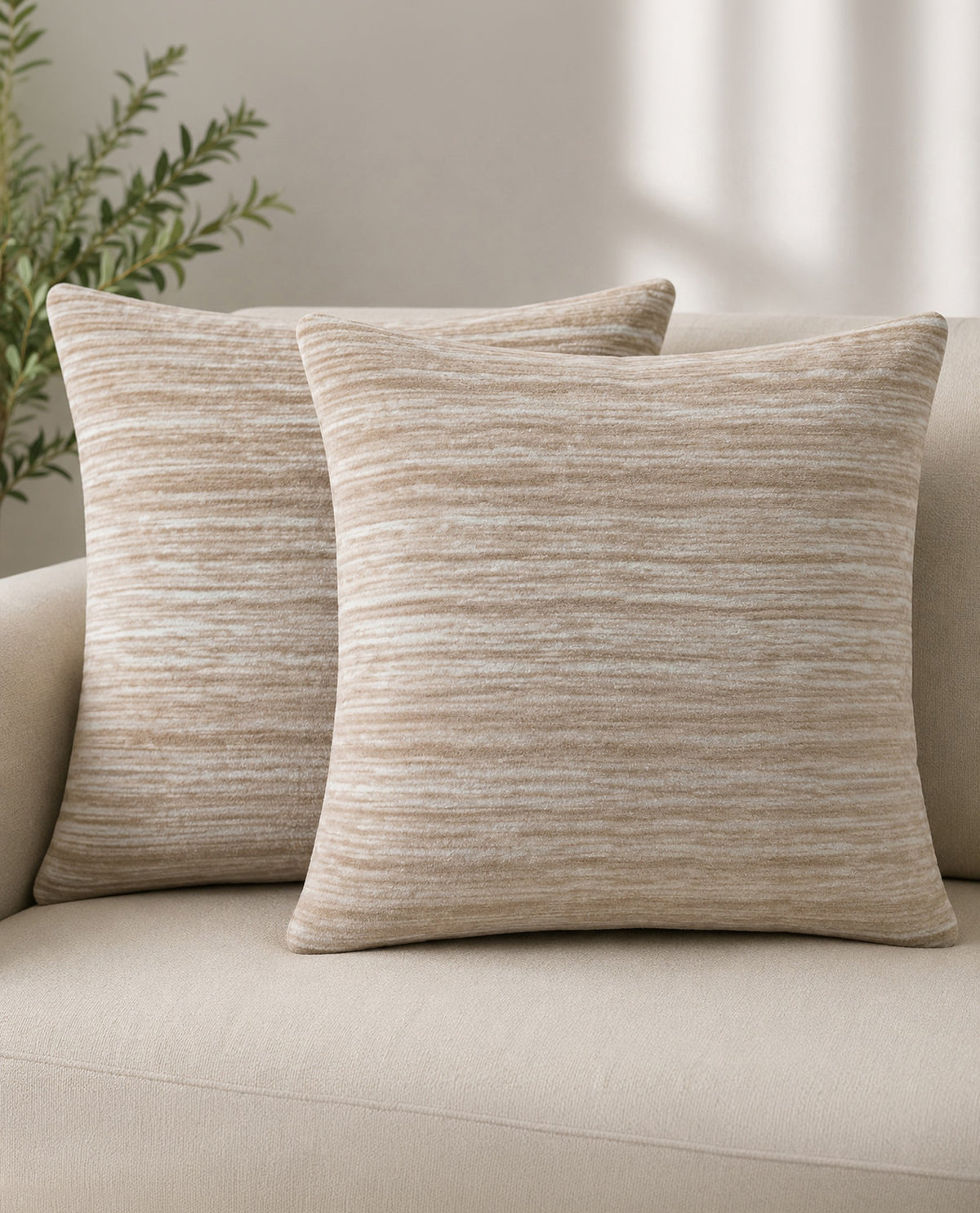Two beige textured pillows on a beige sofa with a neutral background
