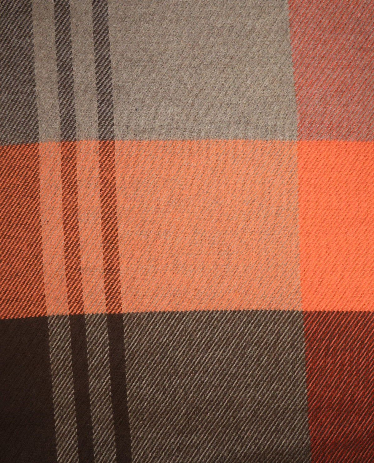 A close-up of a plaid fabric pattern with blocks of orange, brown, gray, and dark brown stripes.