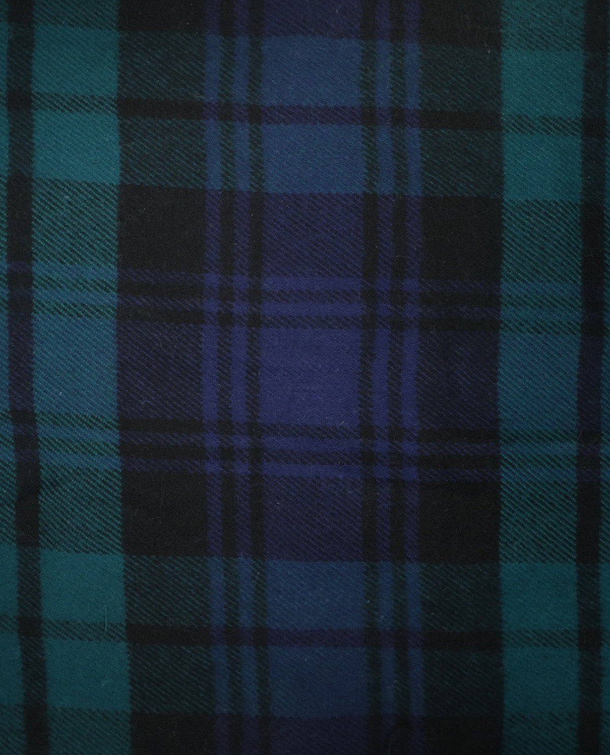 A close-up of a tartan plaid fabric pattern in dark blue, teal, and black.