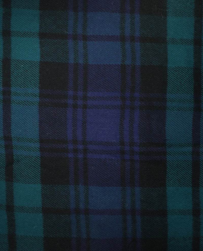 A close-up of a tartan plaid fabric pattern in dark blue, teal, and black.