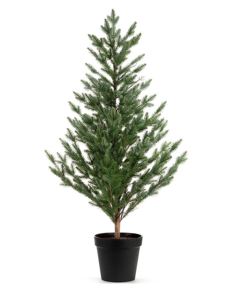 An artificial conifer-style Christmas tree with dense green needles and a brown trunk, potted in a simple black plastic nursery pot against a plain white background.