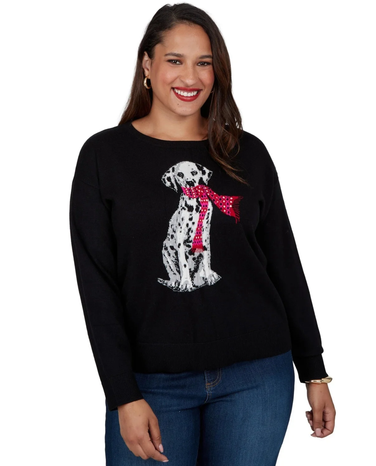 A woman wearing a black crewneck sweater with a white Dalmatian graphic wearing a red polka-dot bow tie, paired with blue jeans against a plain white background.
