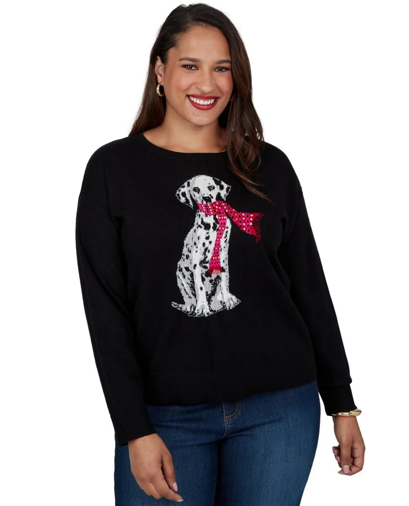A woman wearing a black crewneck sweater with a white Dalmatian graphic wearing a red polka-dot bow tie, paired with blue jeans against a plain white background.