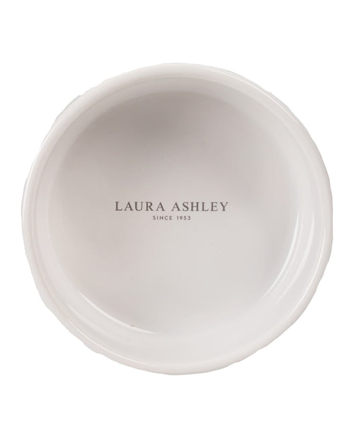 A top-down view of a white ceramic plate with a scalloped rim, featuring the text 'LAURA ASHLEY SINCE 1953' printed in gray in the center.