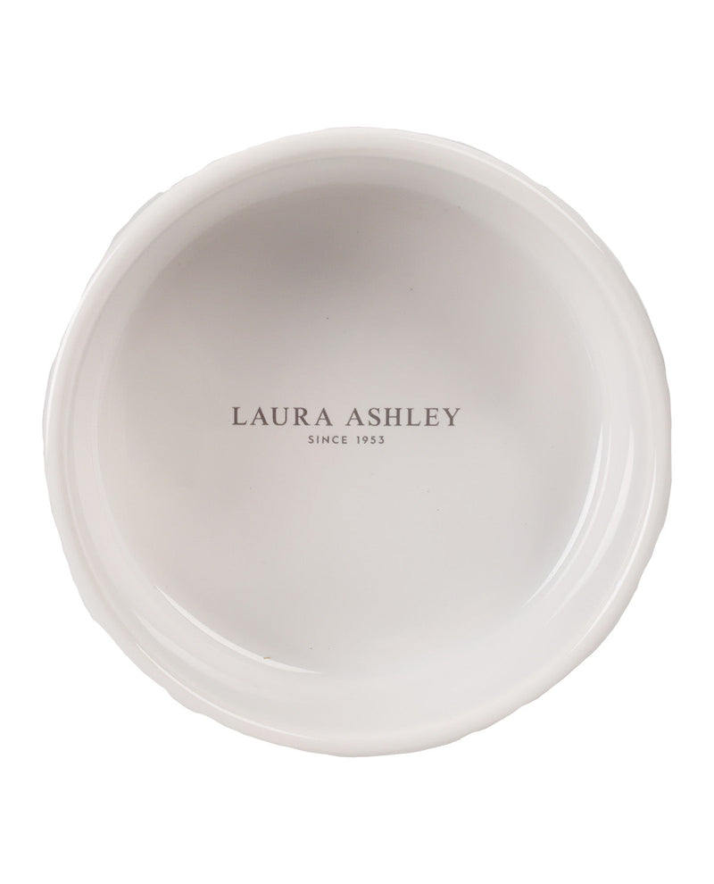 A top-down view of a white ceramic plate with a scalloped rim, featuring the text 'LAURA ASHLEY SINCE 1953' printed in gray in the center.