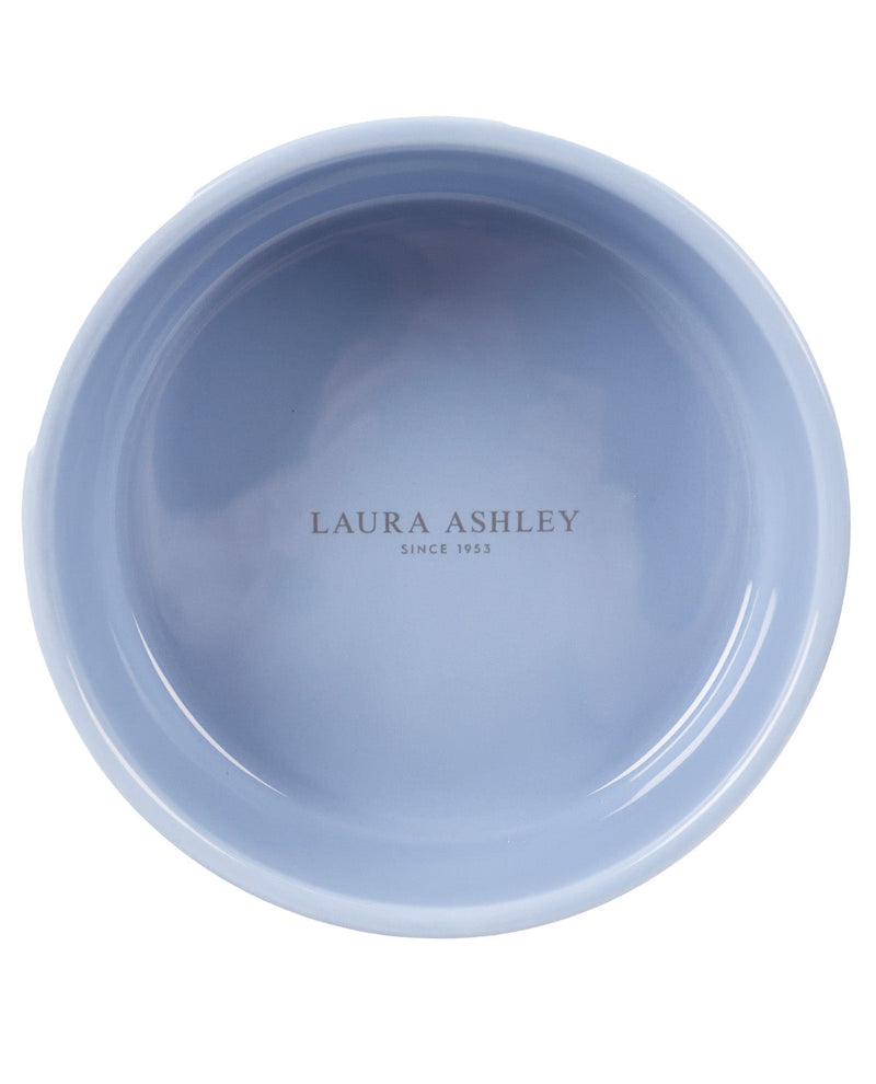 A top-down view of a light blue ceramic bowl with 'LAURA ASHLEY SINCE 1965' printed in the center, on a solid white background.