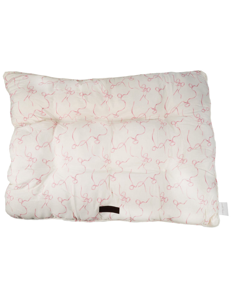 A square quilted cushion or pillow in off-white fabric with a delicate pink abstract line pattern, featuring a small black fabric tag near the bottom center.