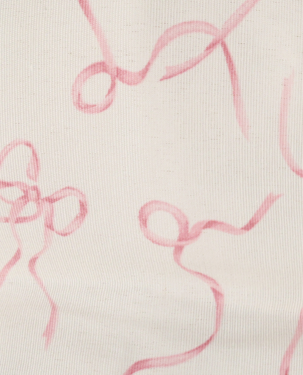 A close-up of a light cream fabric with a pink abstract ribbon or bow print.