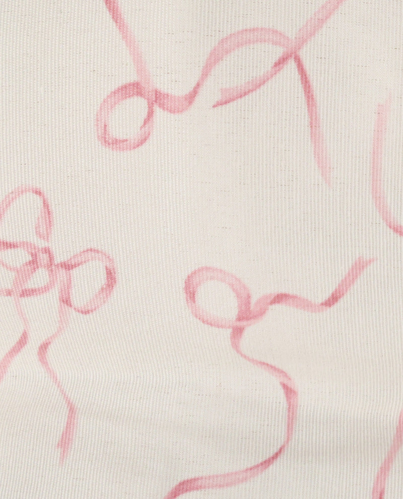 A close-up of a light cream fabric with a pink abstract ribbon or bow print.