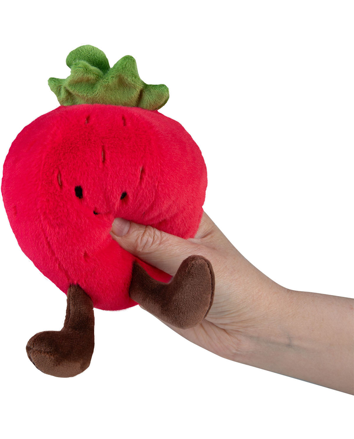 Plush strawberry toy held by a hand on a white background